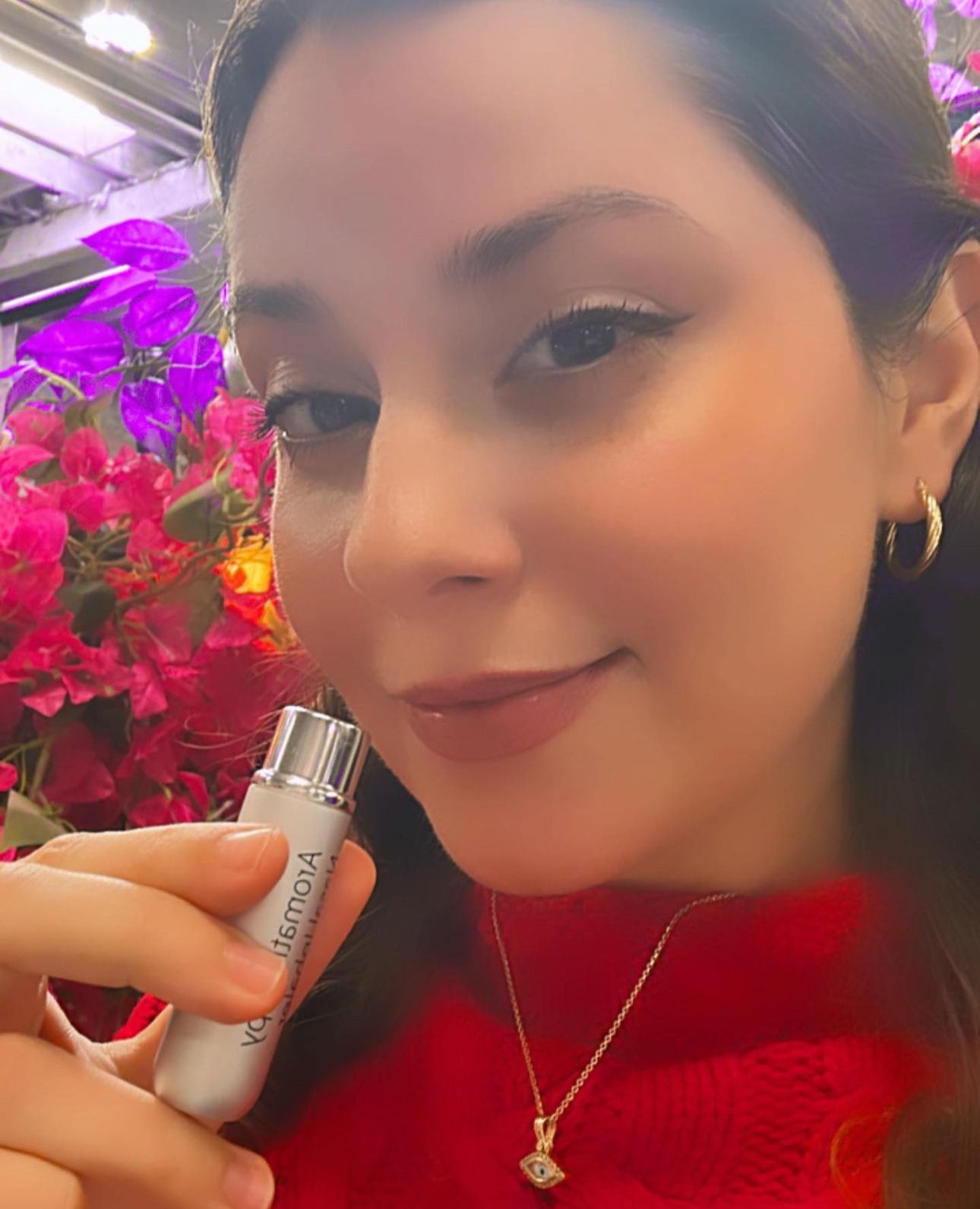 A woman in a red sweater using the aromatherapy inhaler