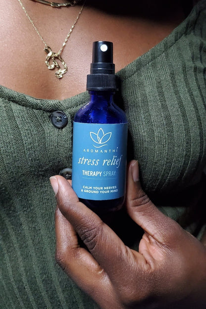 A woman with a green shirt holding the Stress Relief Therapy Spray by aromanthi
