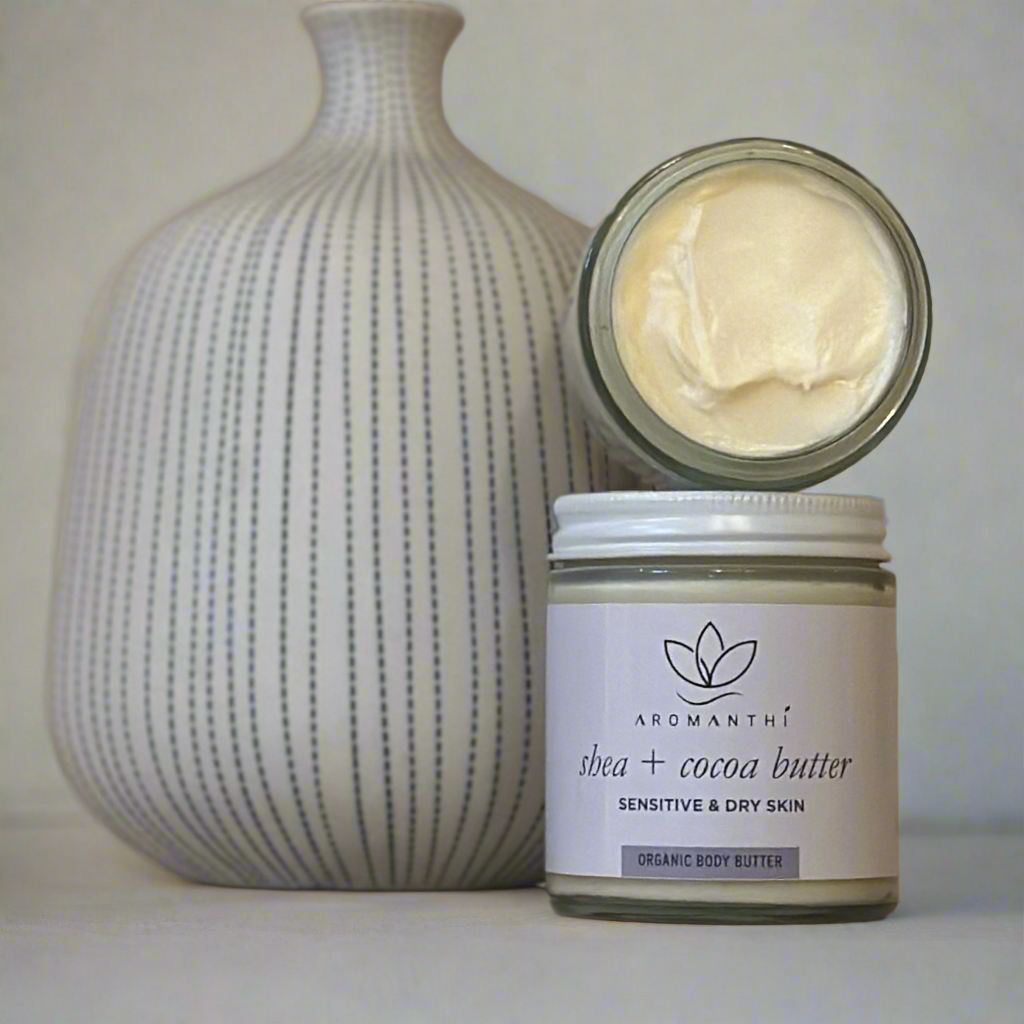 A marble backdrop with a white and blue vase which features the shea and cocoa butter jar, and texture of the whipped formula