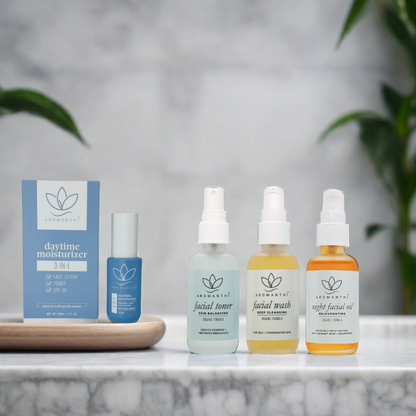 A marble backdrop that has the Aromanthi healthy skincare bundle displayed. Products include 3-in-1 daytime moisturizer, facial wash, facial toner, and night facial oil that is EWG verified. 