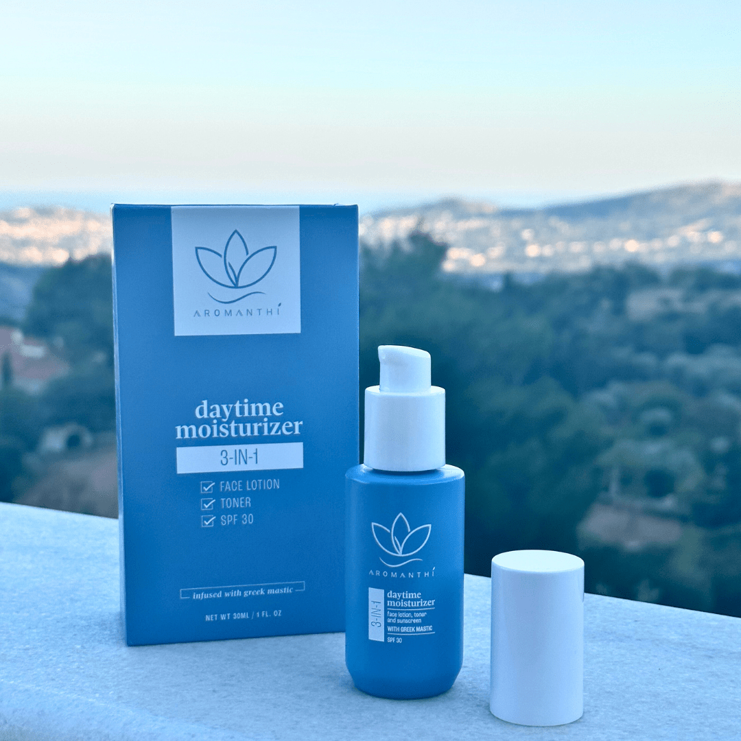 A backdrop photo of the trees and mountains of Greece with the 3-in-1 daytime moisturizer box, bottle and cap displayed on a marble balcony top