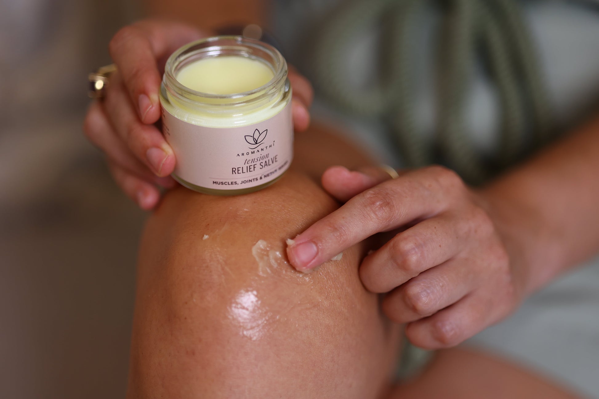 A close up image of the texture of pain salve from aromanthi being applied on a person's knee to manage pain symptoms.