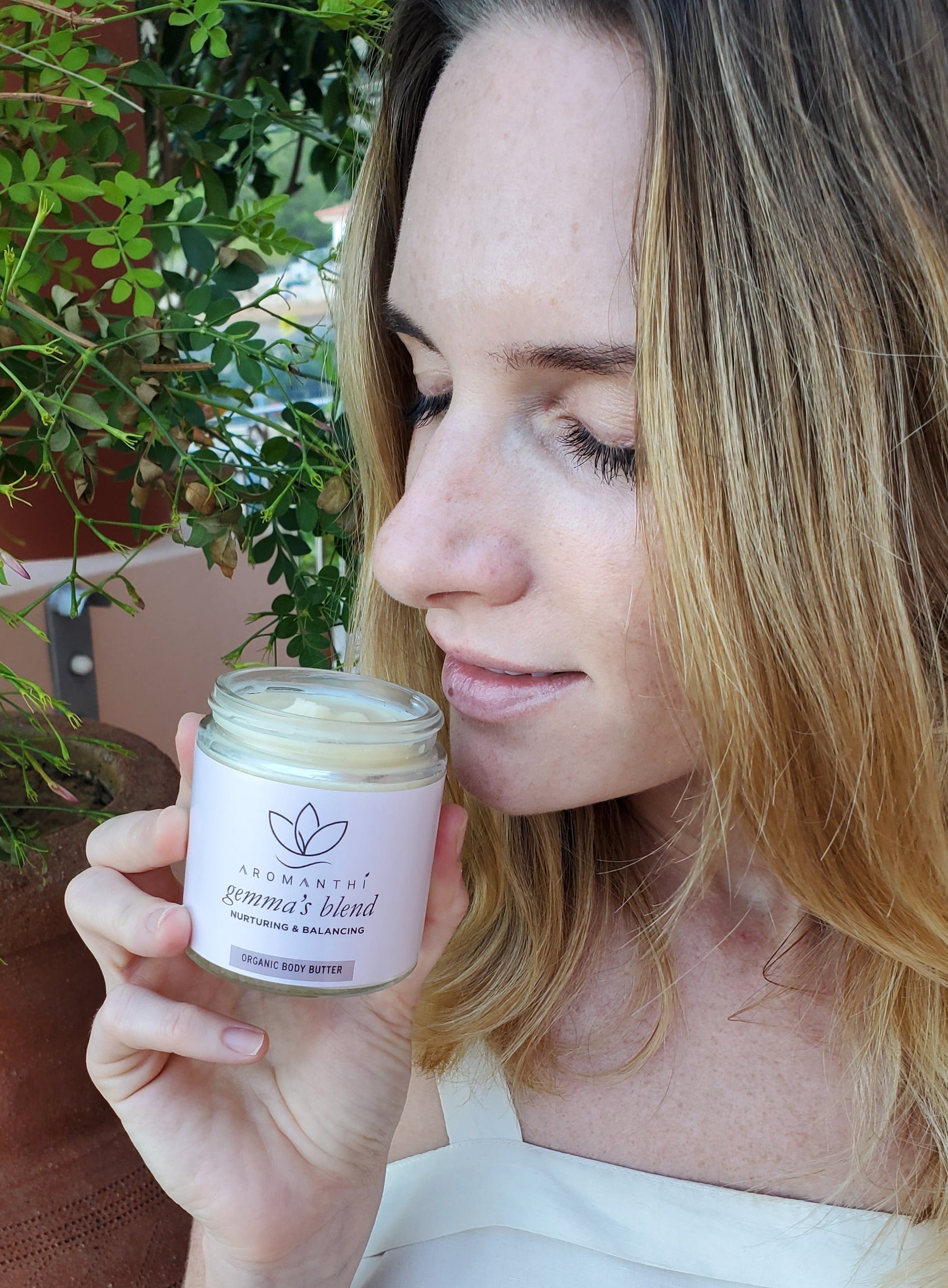 A woman smelling a jar of Gemma's blend body butter by Aromanthi