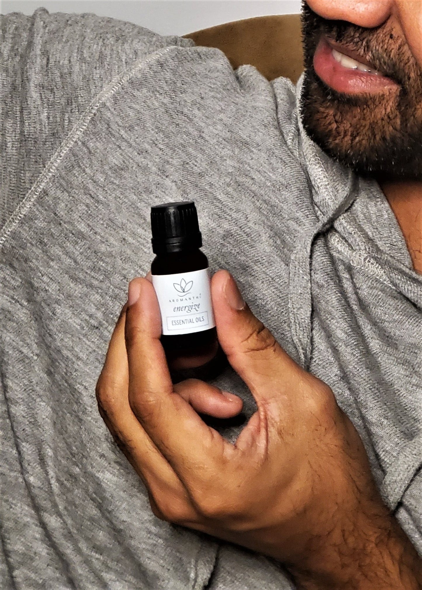 A close up photo of a man holding the Energize Essential Oil Blend 10ml - Aromanthi Clean Beauty & Wellness