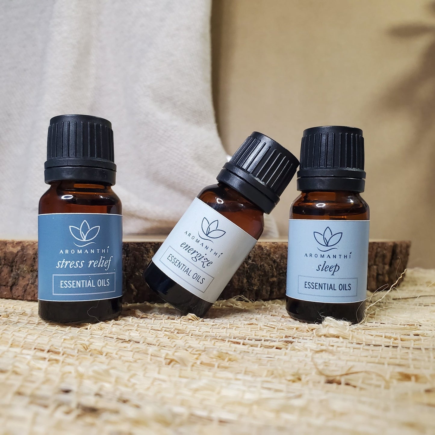 A tan backdrop with linen and natural materials with Aromanthi essential oil collection which includes stress relief, energize and sleep blends all in 10ml size