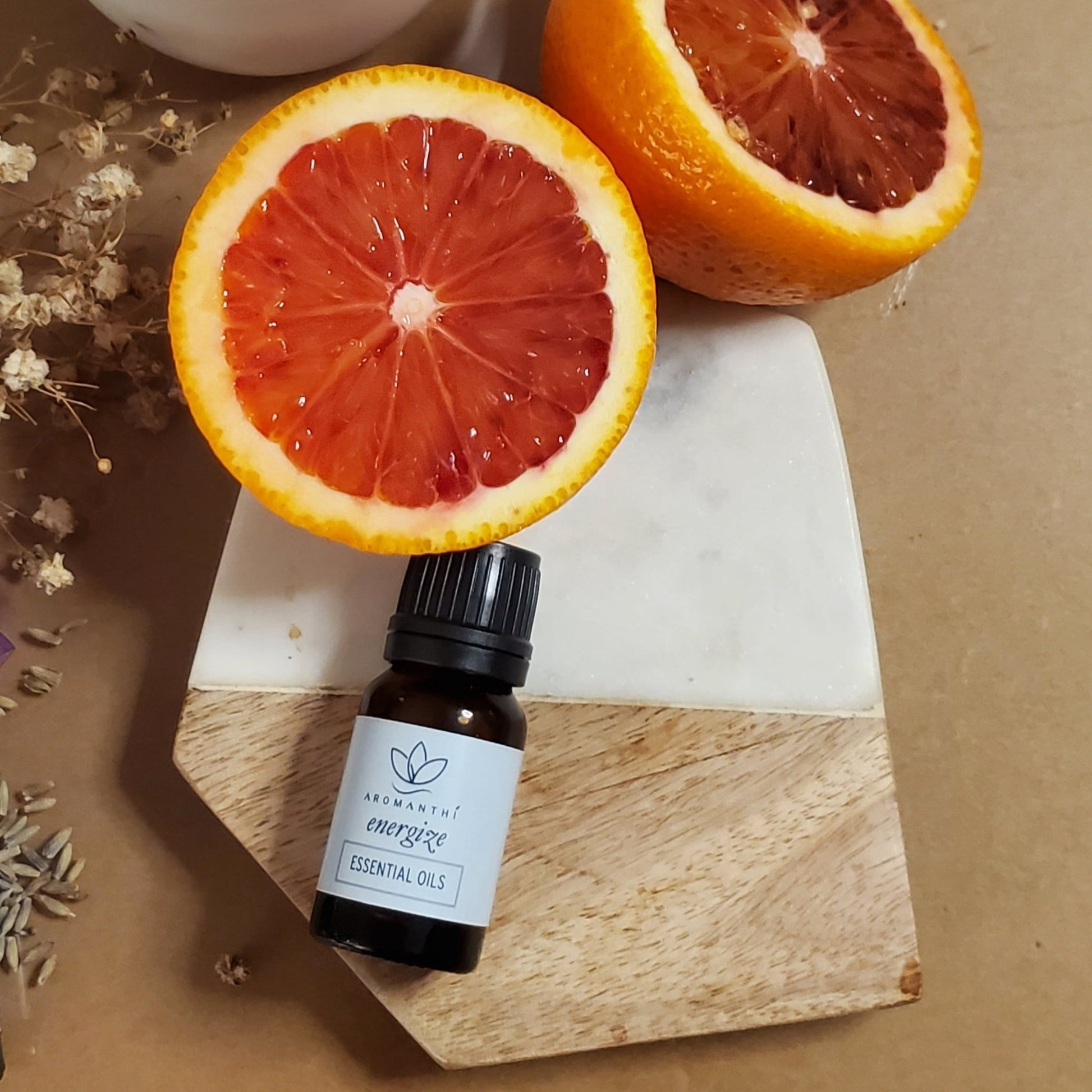 A photo of a tan backdrop with cut up citrus with the energize essential oil blend laying next to it.