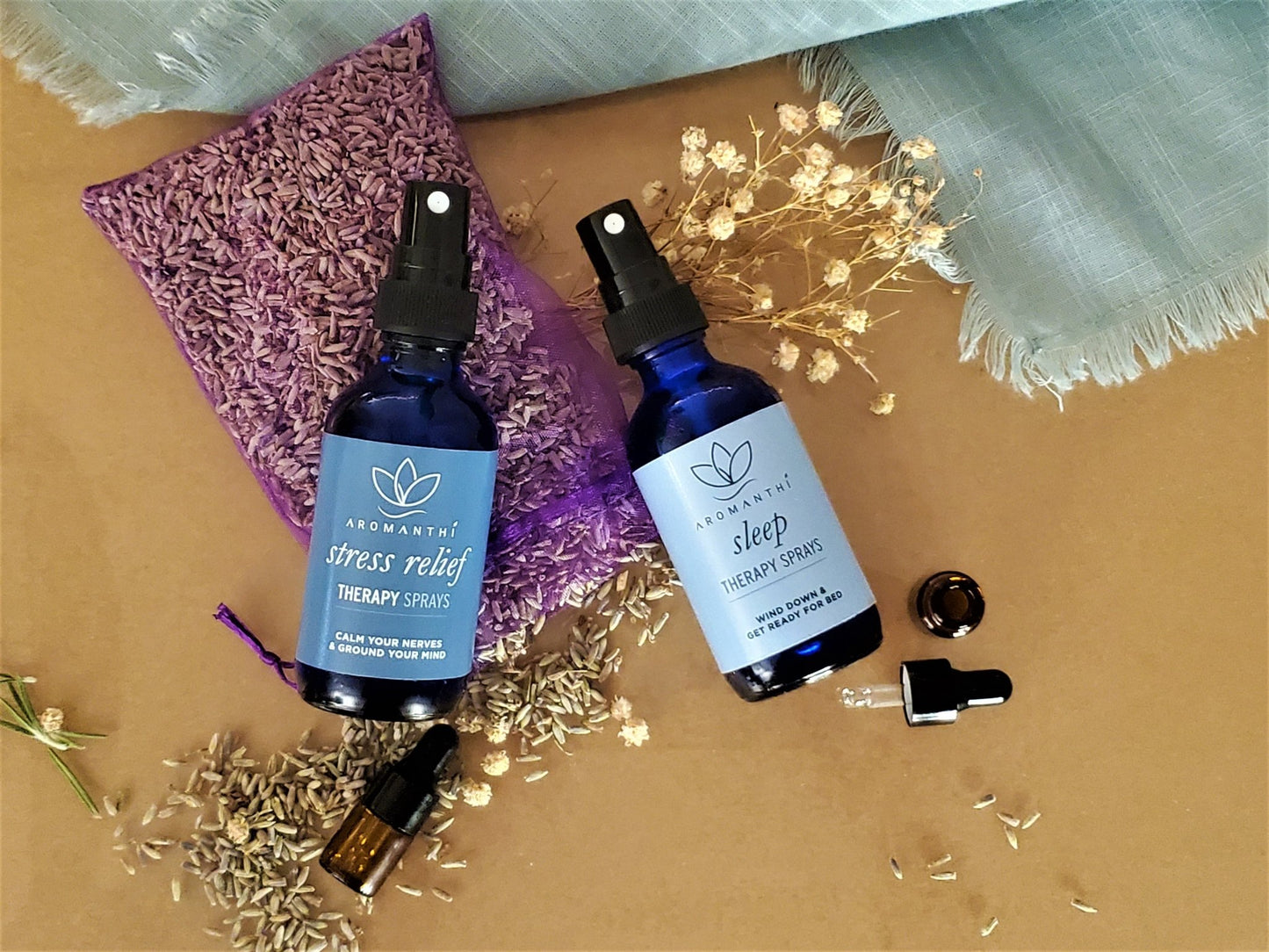 A tan backdrop with dry flower petals surrounding the aromatherapy spray collection which includes stress relief and sleep blends