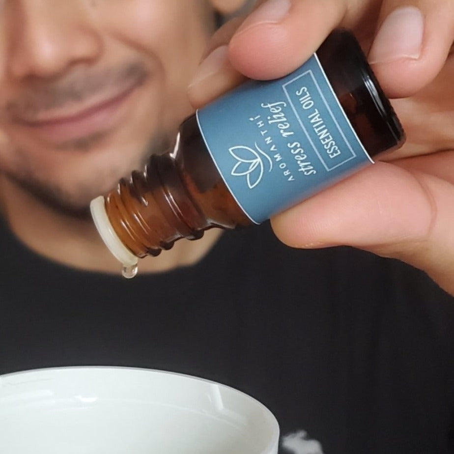 A man holding the bottle of stress relief essential oil blend and adding drop of oil into a diffuser.