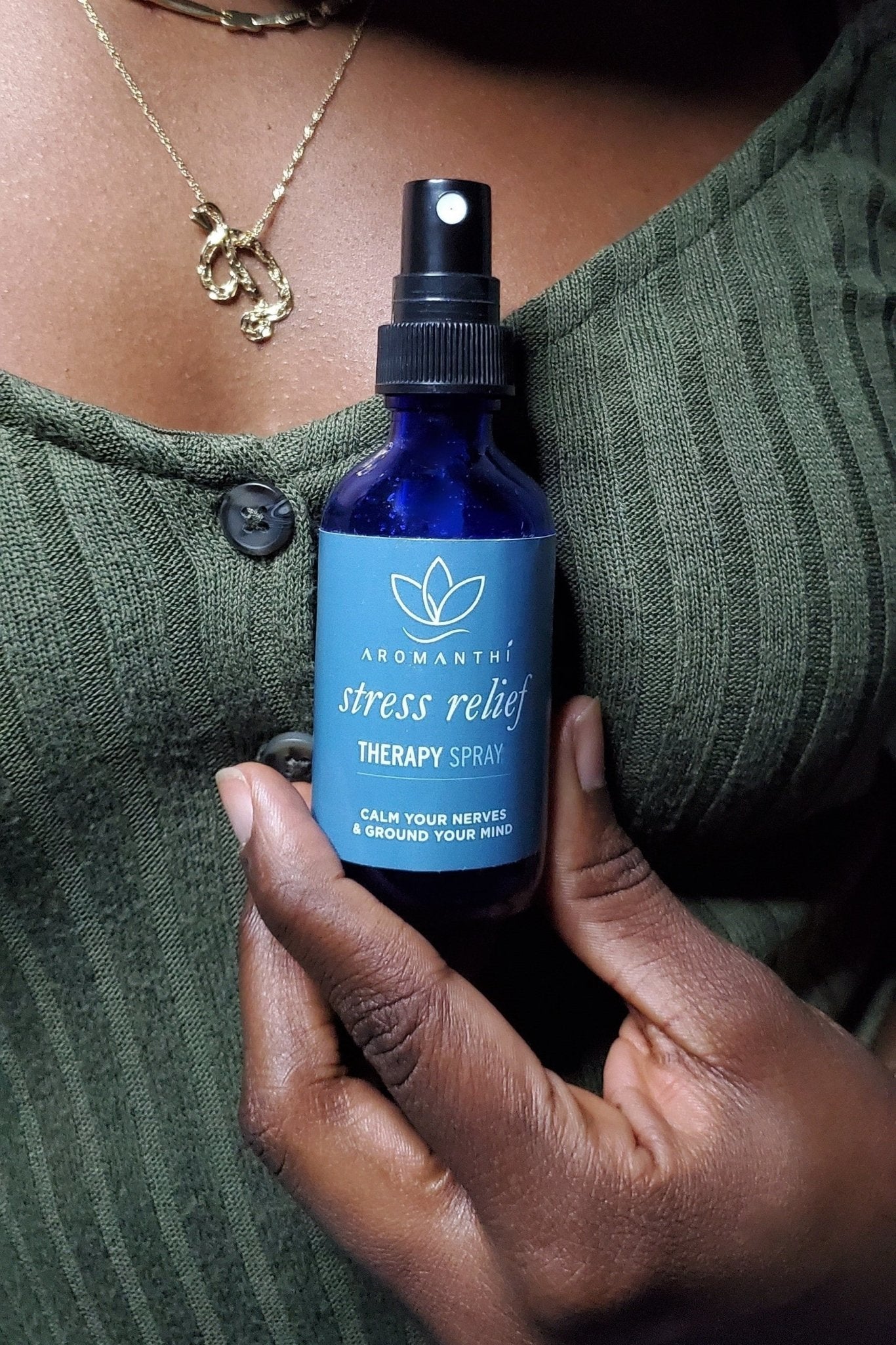 A woman with a green shirt holding the Stress Relief Therapy Spray by aromanthi